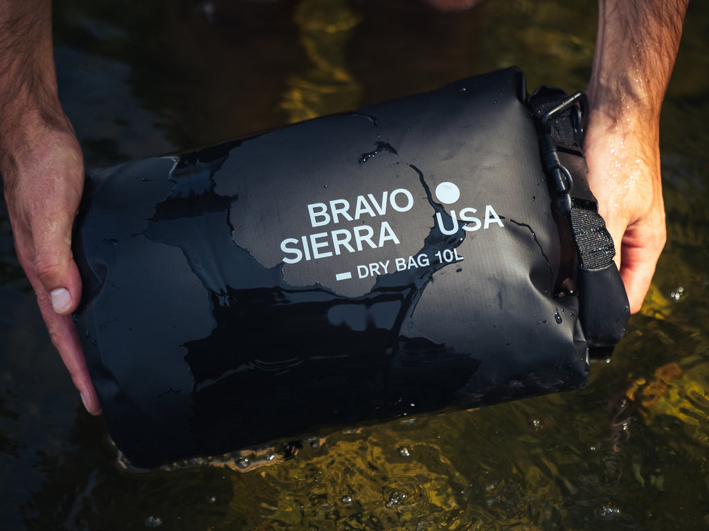 Bravo Sierra 10L dry bag in black, waterproof, ideal for outdoor activities, held above water.