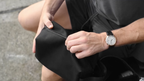 Close-up of a man's hands unzipping a sleek black bag, showcasing durable material and modern design.